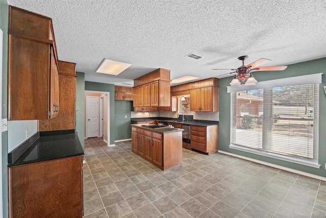 kitchen featuring brown cabinets, dark countertops, visible vents, a ceiling fan, and dishwasher