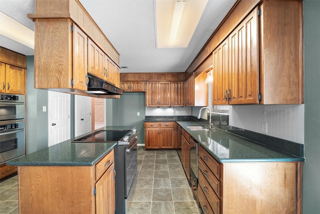 kitchen with under cabinet range hood, stainless steel appliances, a kitchen island, a sink, and brown cabinetry