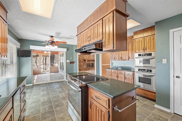 kitchen with dark countertops, electric range, double oven, a kitchen island, and under cabinet range hood