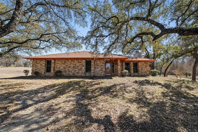 view of front of property featuring a chimney and brick siding