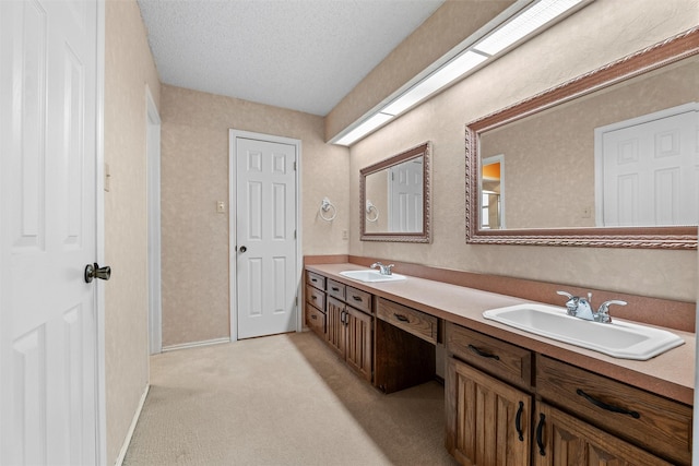 bathroom featuring a sink, a textured ceiling, baseboards, and double vanity