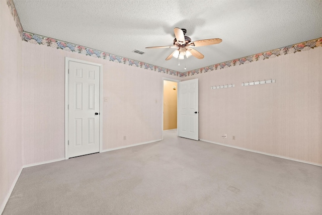 carpeted spare room featuring visible vents, ceiling fan, a textured ceiling, and baseboards