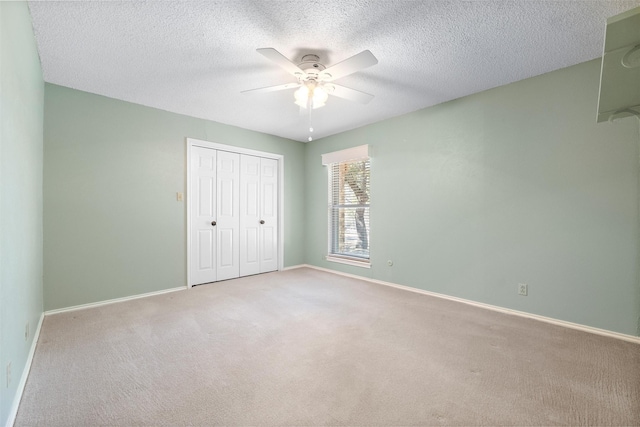 unfurnished bedroom with light carpet, a closet, a textured ceiling, and baseboards