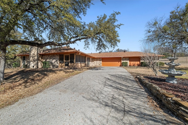 view of front of house featuring stone siding and gravel driveway