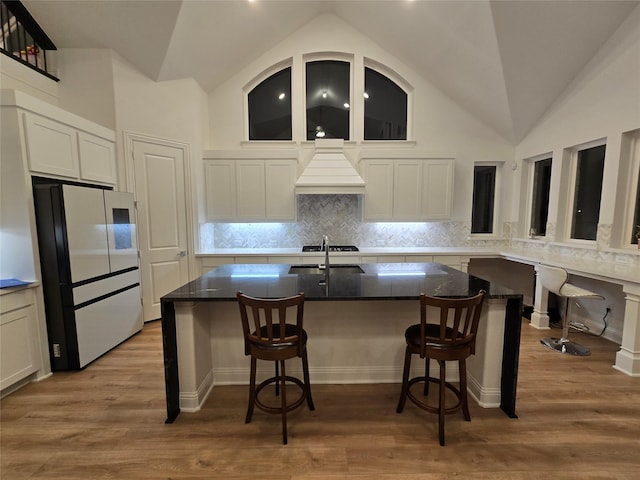 kitchen featuring light wood-style floors, freestanding refrigerator, premium range hood, and white cabinetry