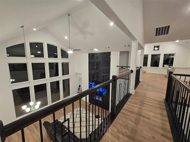 hall featuring high vaulted ceiling, visible vents, wood finished floors, and an upstairs landing