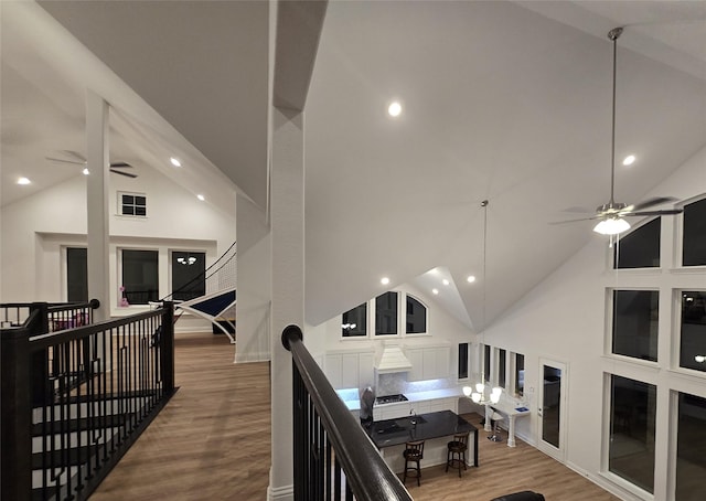 hallway with high vaulted ceiling, recessed lighting, an upstairs landing, and wood finished floors