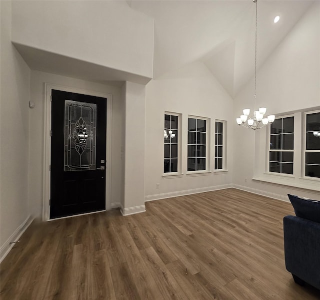 foyer with a chandelier, high vaulted ceiling, baseboards, and wood finished floors