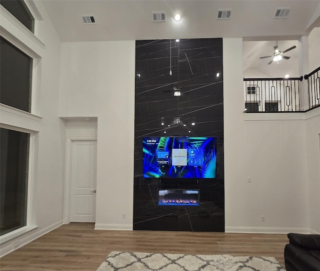 unfurnished living room featuring a towering ceiling, wood finished floors, and visible vents