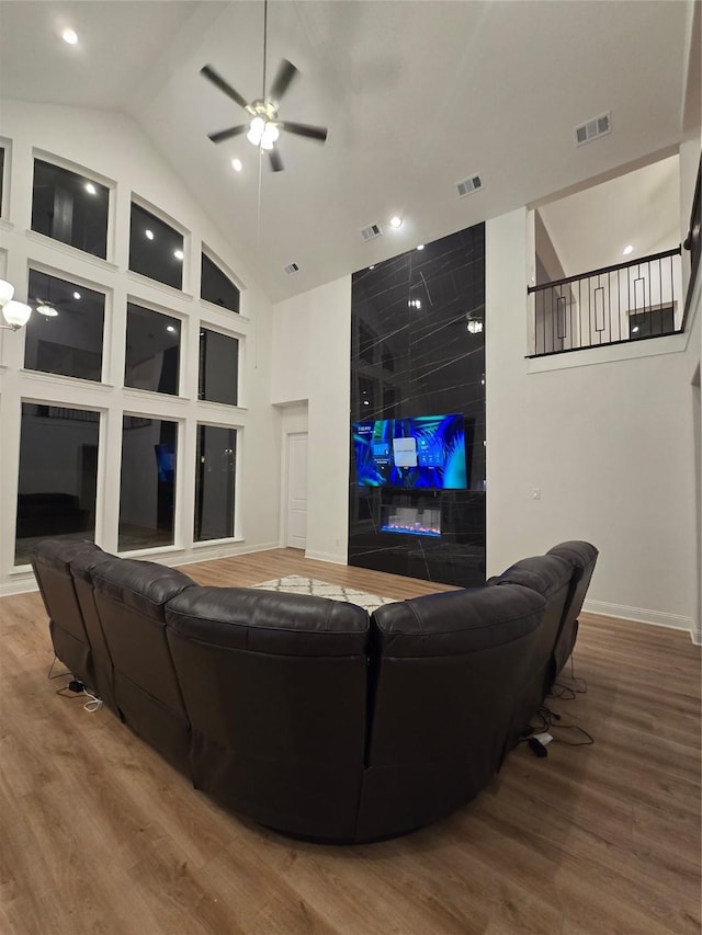 living area featuring high vaulted ceiling, visible vents, ceiling fan, and wood finished floors