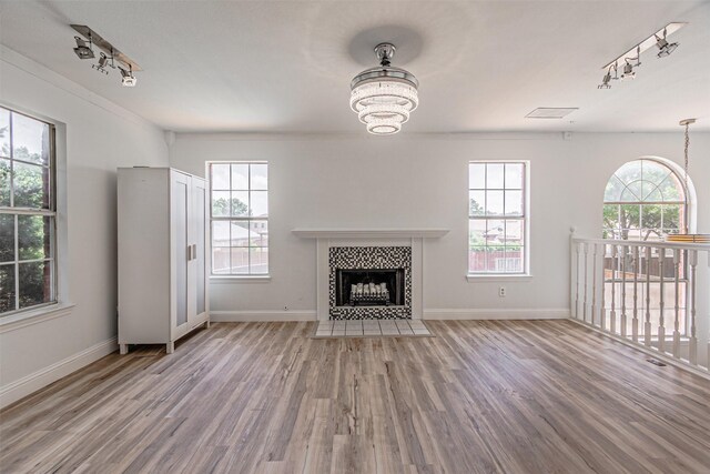 1542 Home Park Dr, Allen, TX 75002 - unfurnished living room featuring track lighting, wood finished floors, a tile fireplace, a chandelier, and baseboards