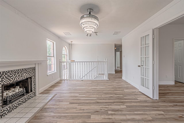 1542 Home Park Dr, Allen, TX 75002 - unfurnished living room featuring a chandelier, light wood-style flooring, baseboards, a tiled fireplace, and crown molding