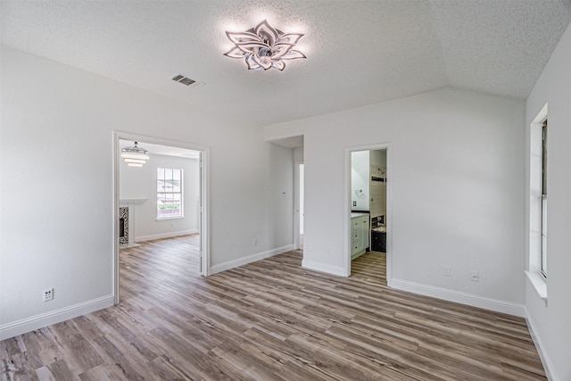 1542 Home Park Dr, Allen, TX 75002 - unfurnished living room with a textured ceiling, wood finished floors, vaulted ceiling, and baseboards
