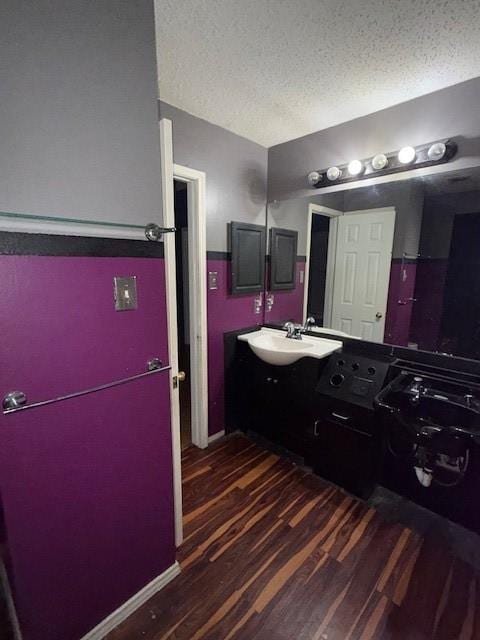 bathroom with baseboards, a textured ceiling, vanity, and wood finished floors