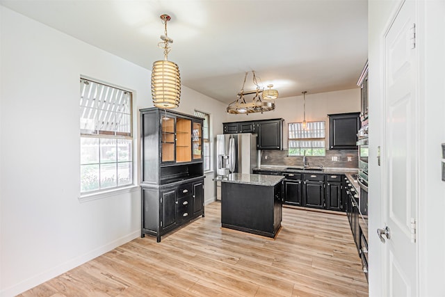 1542 Home Park Dr, Allen, TX 75002 - kitchen featuring a kitchen island, tasteful backsplash, dark cabinetry, light wood-style floors, and light stone counters