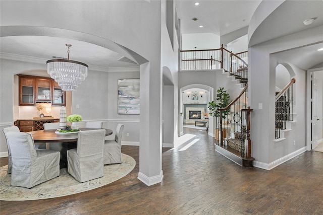 foyer featuring a glass covered fireplace, arched walkways, stairway, and wood-type flooring