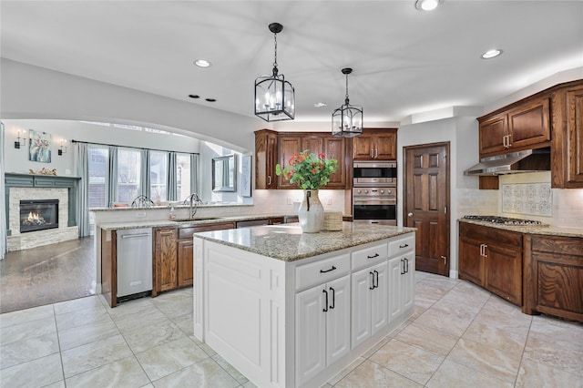 kitchen featuring a sink, decorative backsplash, under cabinet range hood, a kitchen island, and appliances with stainless steel finishes