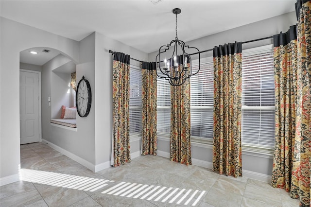 unfurnished dining area featuring arched walkways, visible vents, baseboards, and a notable chandelier