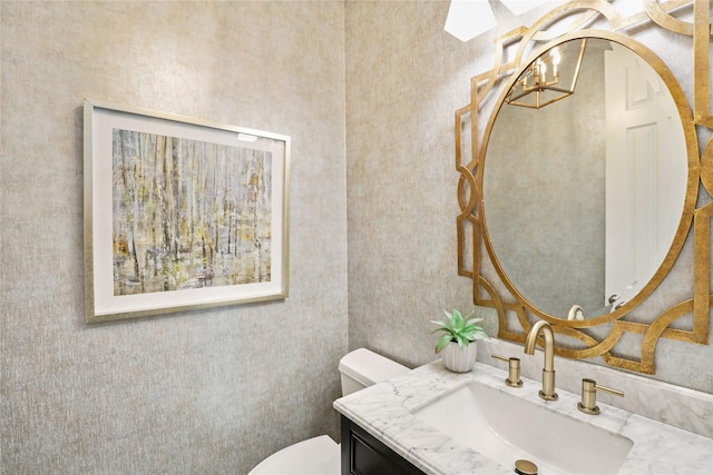 half bathroom featuring toilet, vanity, and a notable chandelier