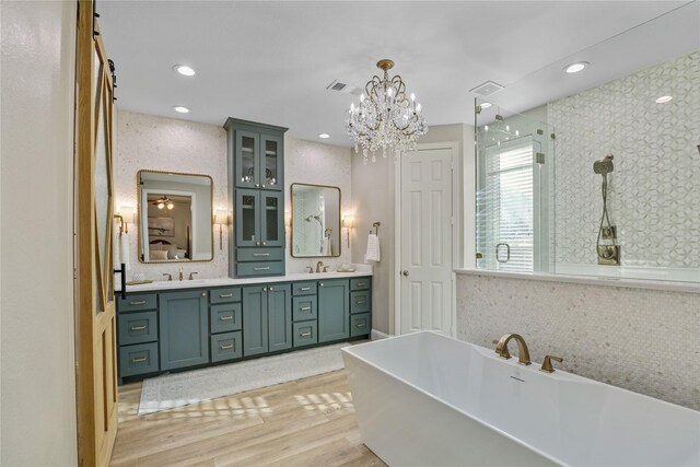 bathroom featuring a sink, double vanity, a freestanding tub, wood finished floors, and a shower stall