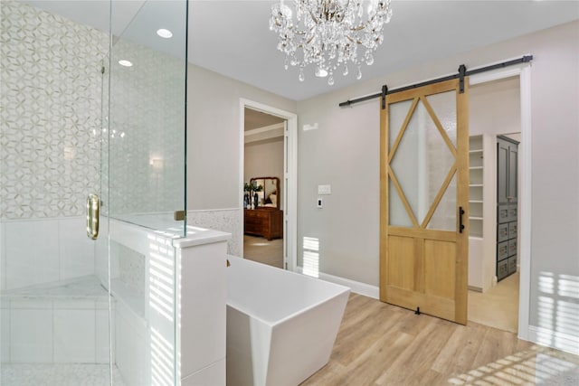 bathroom with a shower stall, wood finished floors, wainscoting, an inviting chandelier, and recessed lighting