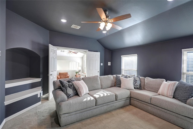 carpeted living area with lofted ceiling, baseboards, visible vents, and ceiling fan