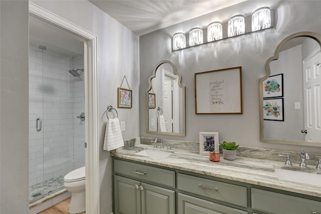bathroom featuring toilet, a sink, double vanity, and a stall shower