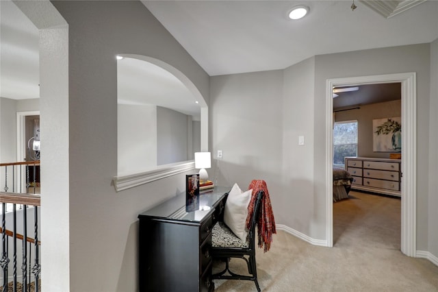 hallway with arched walkways, light carpet, and baseboards