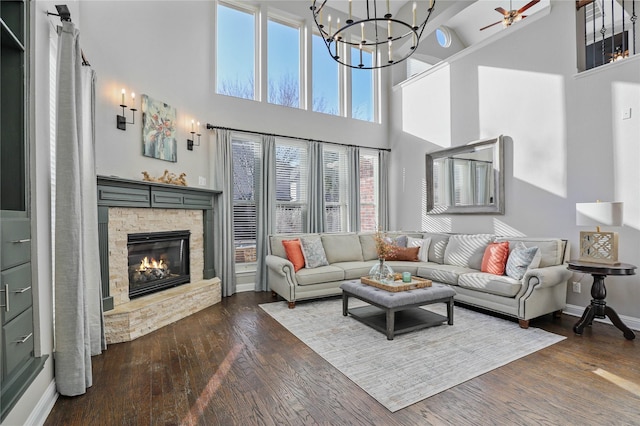 living area with baseboards, a high ceiling, a fireplace, and dark wood-type flooring