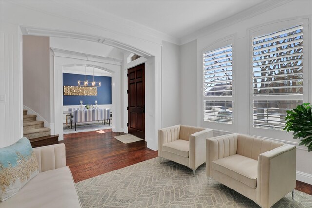 foyer entrance with a notable chandelier, crown molding, wood finished floors, and radiator