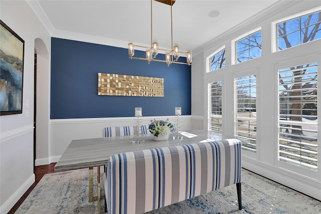 dining room with a notable chandelier, baseboards, wood finished floors, and crown molding