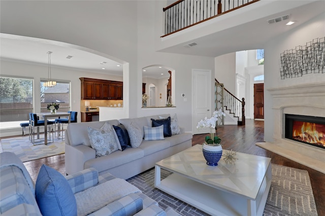 living room with a towering ceiling, dark wood finished floors, and visible vents