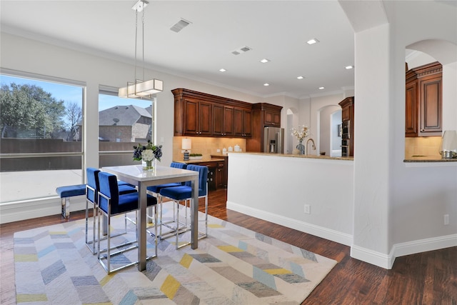 dining area featuring arched walkways, crown molding, recessed lighting, light wood-style floors, and baseboards