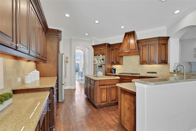 kitchen with arched walkways, appliances with stainless steel finishes, ornamental molding, dark wood-type flooring, and custom exhaust hood