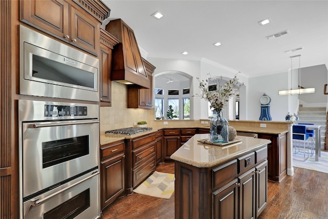 kitchen with dark wood-style floors, a peninsula, appliances with stainless steel finishes, and decorative backsplash