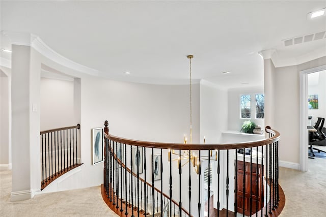 hall with ornamental molding, light colored carpet, visible vents, and an upstairs landing