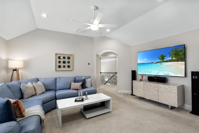 living room featuring arched walkways, baseboards, light colored carpet, ceiling fan, and vaulted ceiling