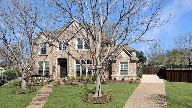 view of front of home featuring brick siding, a front lawn, and fence