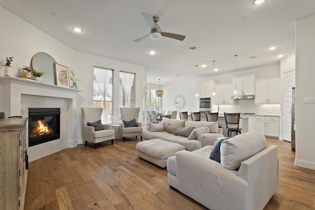 living room featuring a fireplace, recessed lighting, visible vents, ceiling fan, and light wood-type flooring