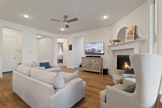 living room with a ceiling fan, a glass covered fireplace, wood finished floors, and recessed lighting