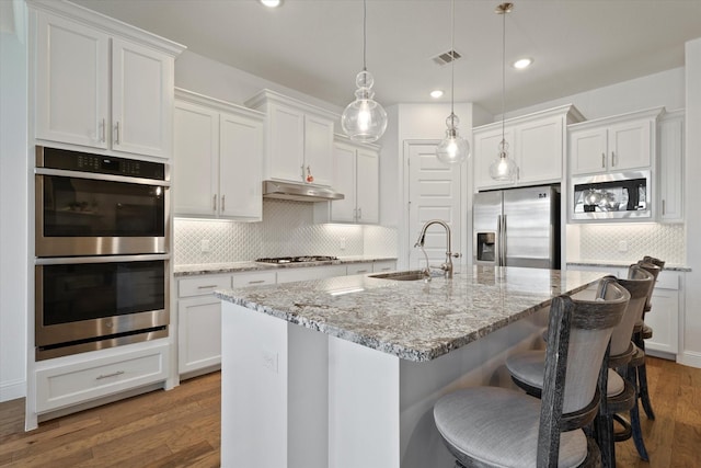 kitchen featuring under cabinet range hood, a sink, white cabinetry, visible vents, and appliances with stainless steel finishes