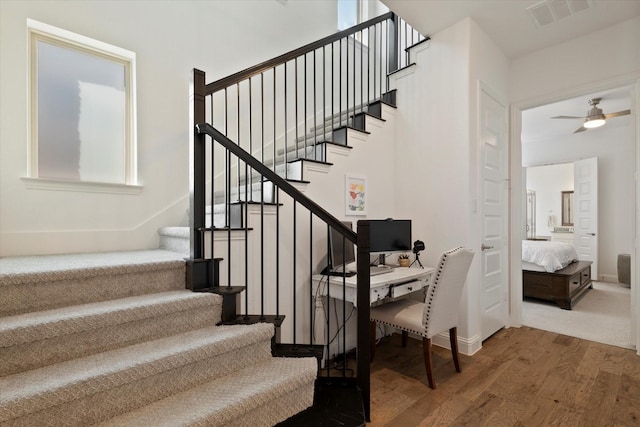 stairway with a ceiling fan, visible vents, and wood finished floors