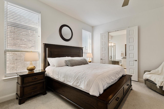 bedroom featuring light carpet, ensuite bath, baseboards, and a ceiling fan