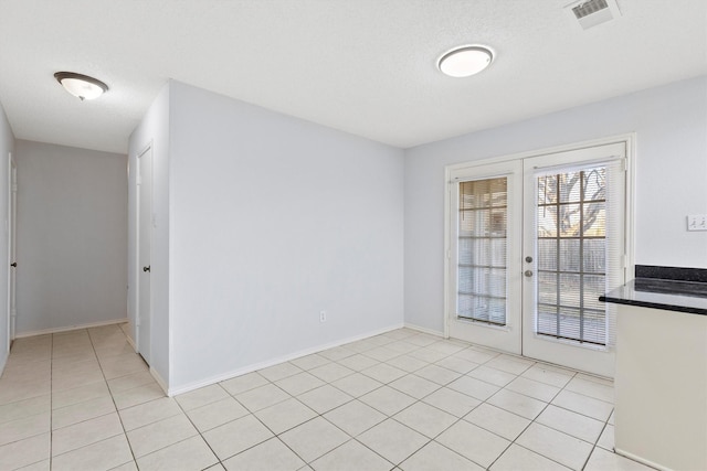 interior space with french doors, light tile patterned floors, visible vents, a textured ceiling, and baseboards