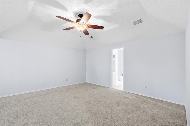 spare room with vaulted ceiling, carpet floors, a textured ceiling, and visible vents