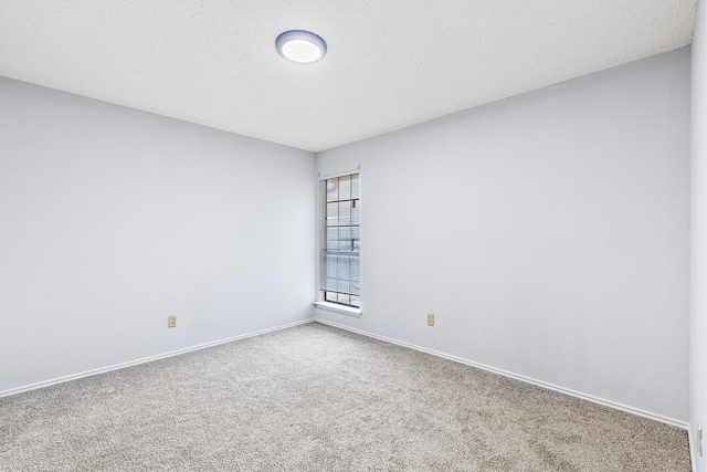 empty room with a textured ceiling, carpet floors, and baseboards