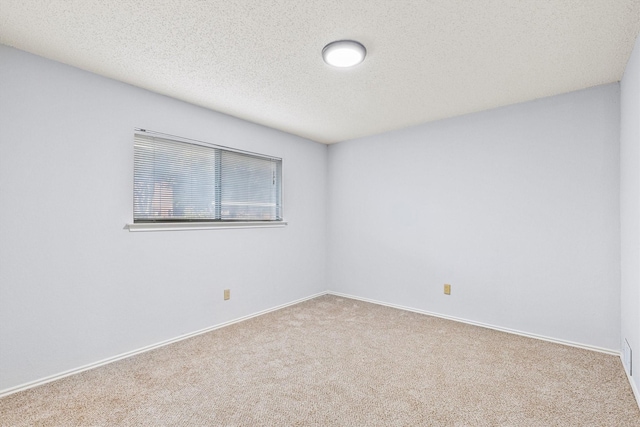 carpeted empty room with baseboards and a textured ceiling