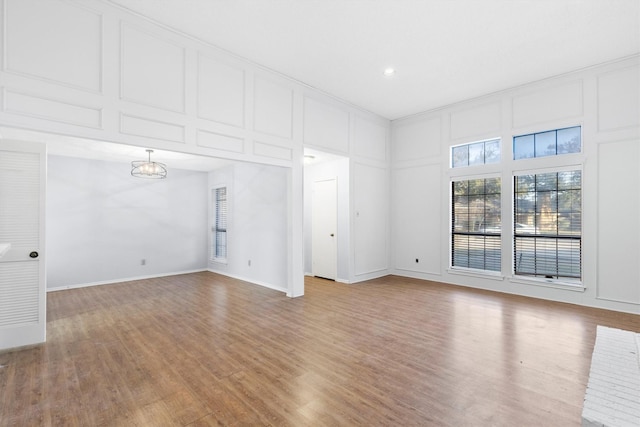 spare room featuring light wood-style floors, a decorative wall, and baseboards