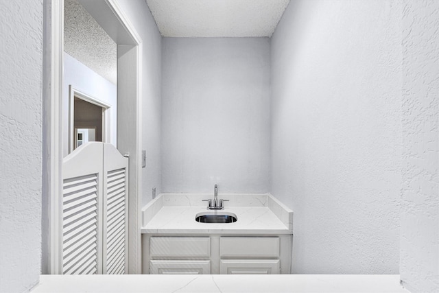 bathroom featuring a textured wall, a sink, and a textured ceiling