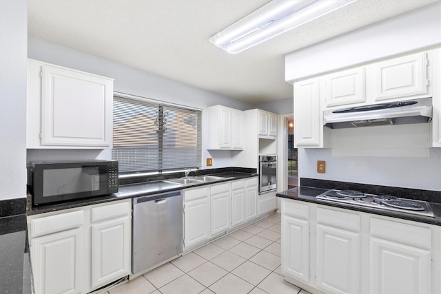 kitchen with under cabinet range hood, stainless steel appliances, a sink, white cabinetry, and dark countertops